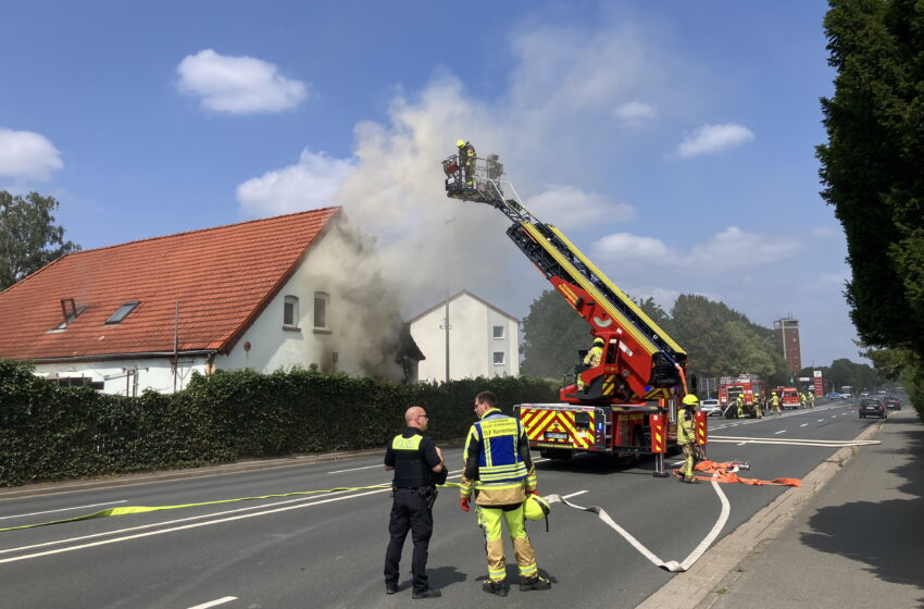 Ein Foto, das eine Drehleiter und Einsatzkräfte vor einem brennenden Gebäude zeigt.
